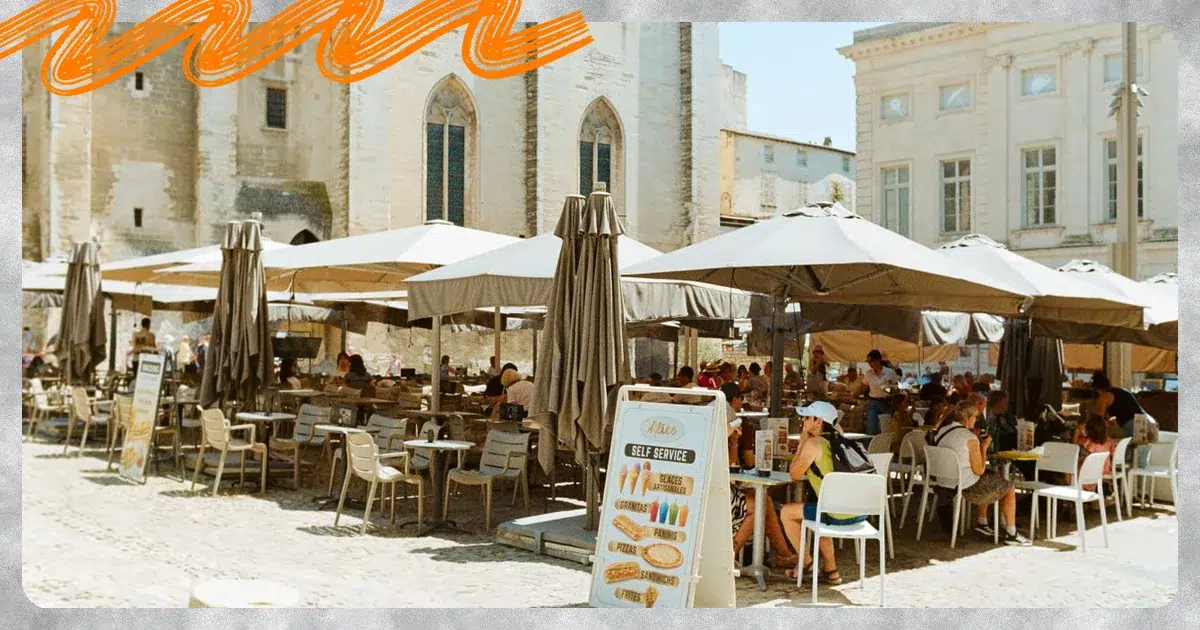 Terrasse animée d'un café devant le Palais des Papes à Avignon, illustration d'un séjour étudiant en stage ou alternance