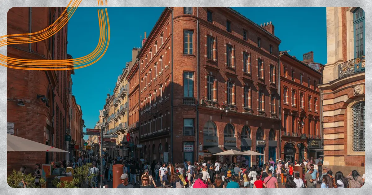Façades en brique rose et passants au centre de Toulouse
