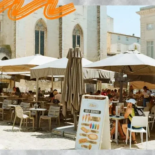Terrasse animée d'un café devant le Palais des Papes à Avignon, illustration d'un séjour étudiant en stage ou alternance