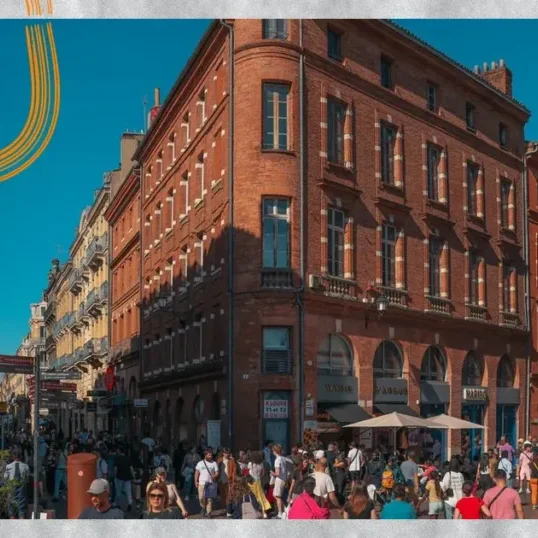 Façades en brique rose et passants au centre de Toulouse